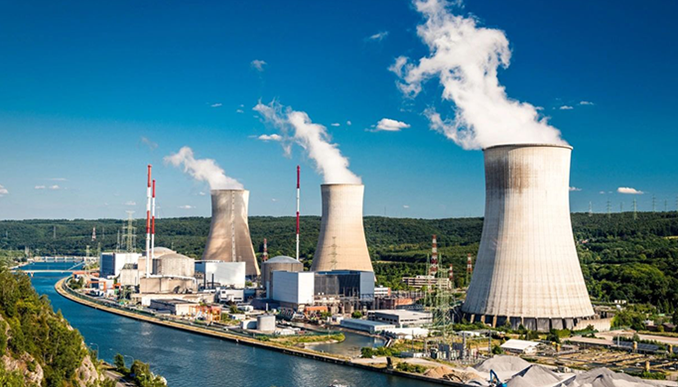 A large power plant with cooling towers and water.