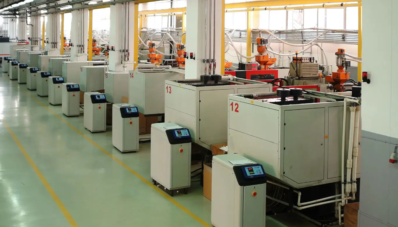 A factory with machines and workers in orange vests.